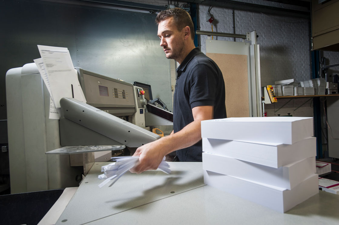 worker-disposing-of-paper-trimmings-in-print-works-2024-06-04-19-48-35-utc